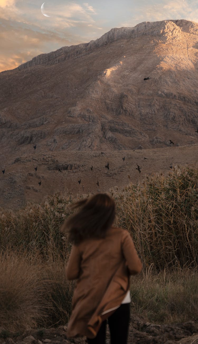 Woman In Brown Coat Running Through Prairie