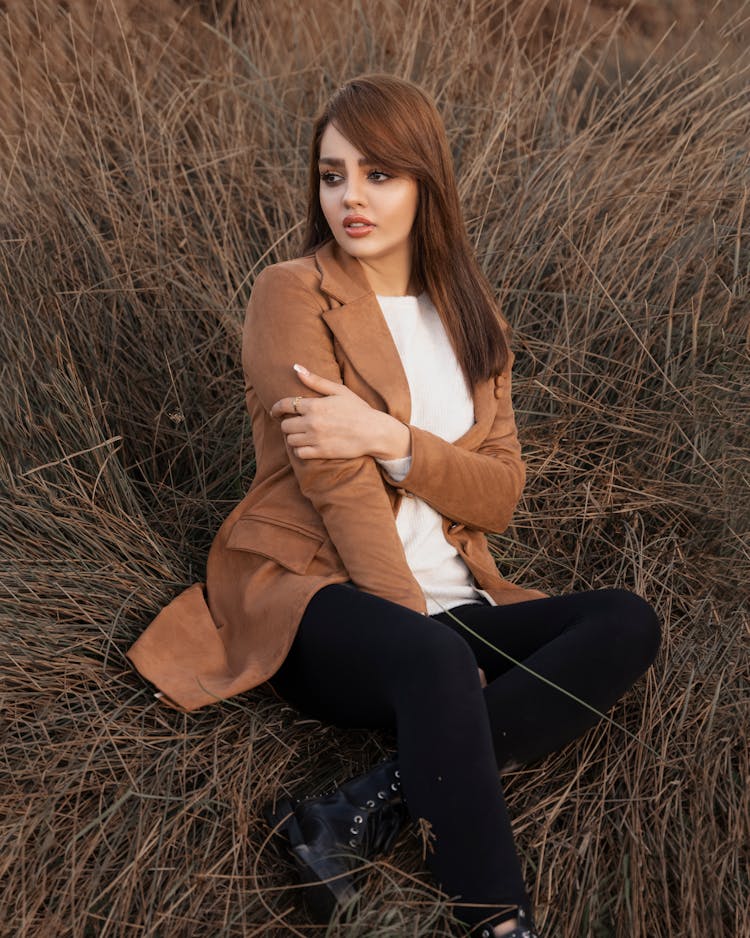 Woman Sitting In Dried Grass