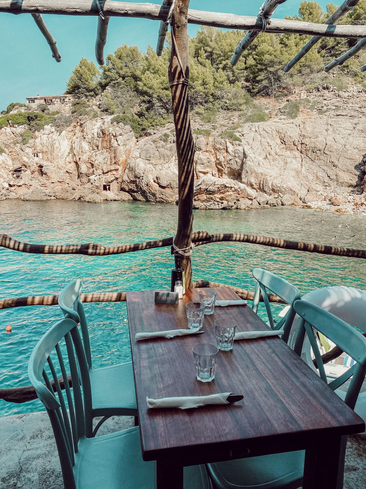 Wooden chairs and table near a body of water at a romantic Ibiza restaurant