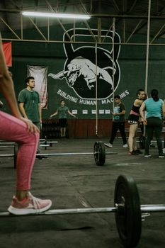 Participants engaged in a lively crossfit session at a gym featuring weightlifting and team exercises.