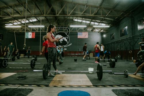 Free Group of adults practicing CrossFit with weights in an industrial-style gym. Stock Photo