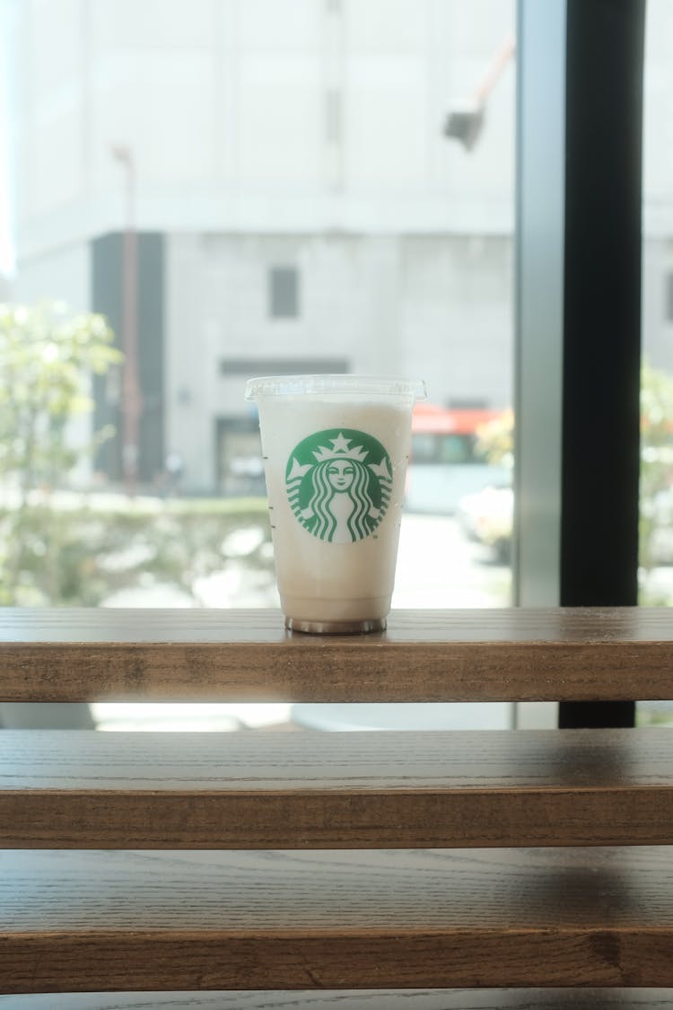 Plastic Starbucks Cup On Brown Wooden Shelves