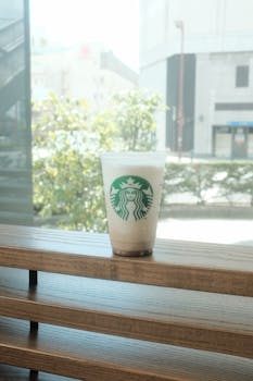 Iced coffee on wooden table by a window showing an outdoor view.