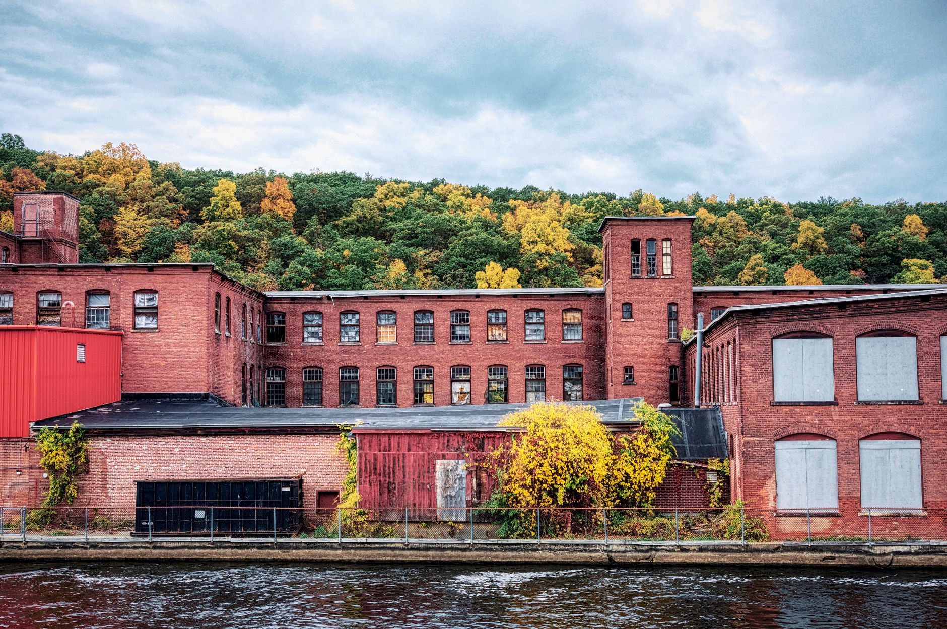Abandoned factory in Montague, MA with autumn foliage reflecting on river