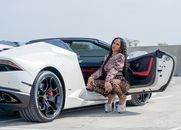 Woman in Printed Clothing and High Heels Crouching Near a White Car