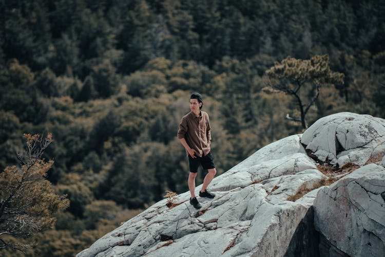 Man Posing On Rocks With Forest Below