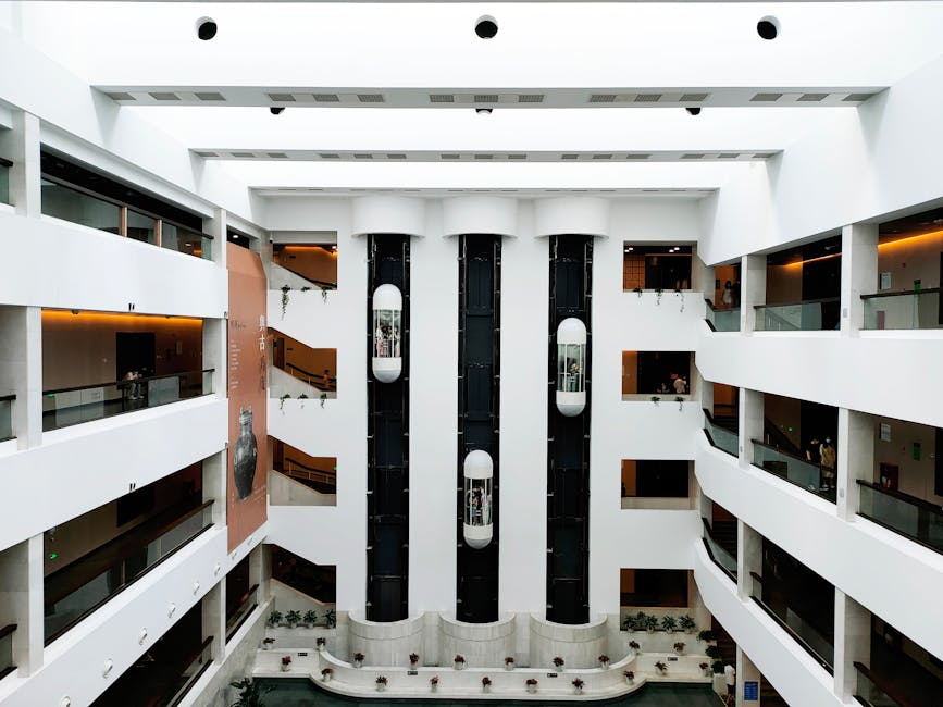 A spacious, contemporary atrium featuring sleek glass elevators and modern architectural elements.