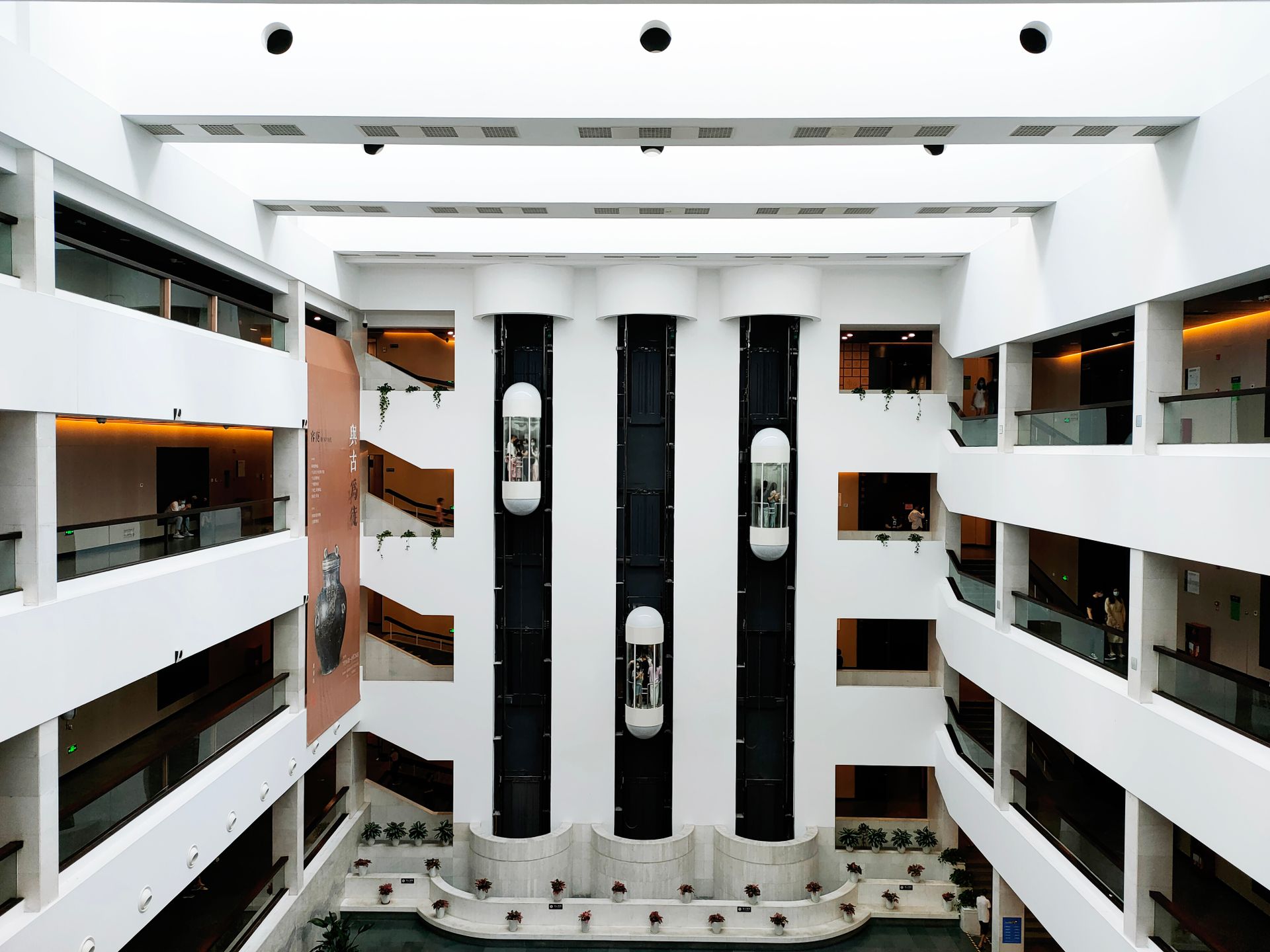 A spacious, contemporary atrium featuring sleek glass elevators and modern architectural elements.