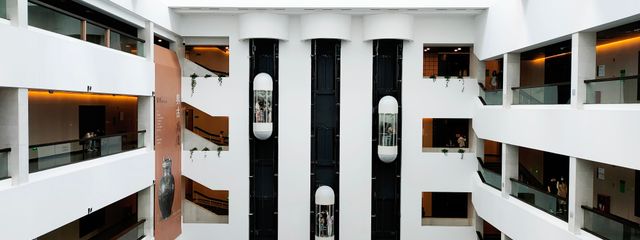 A spacious, contemporary atrium featuring sleek glass elevators and modern architectural elements.