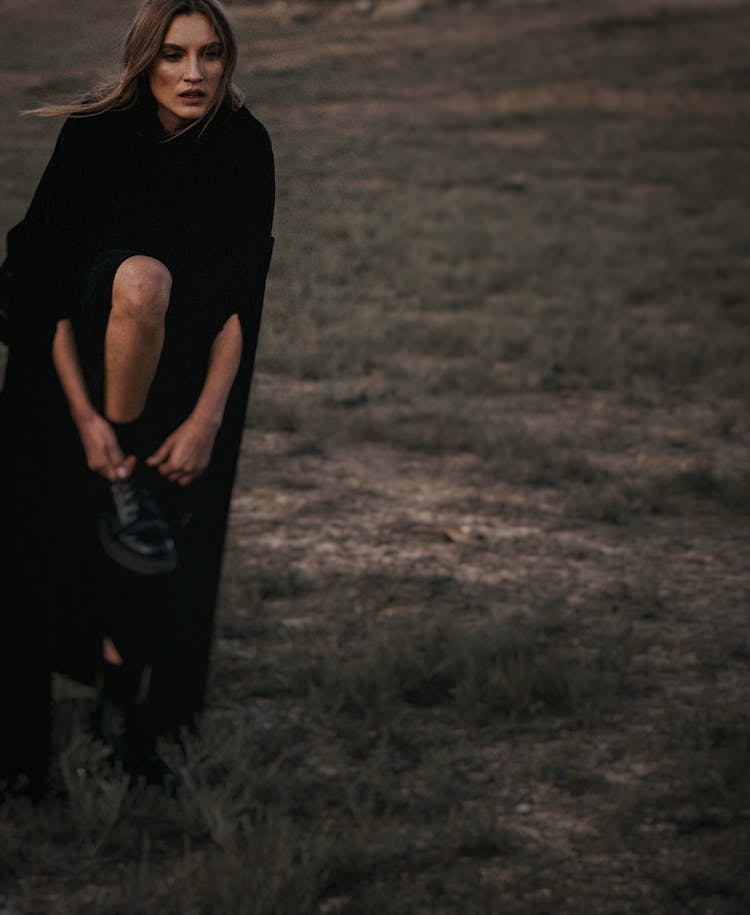 Portrait Of Woman In Black Cloths Tying Her Shoe