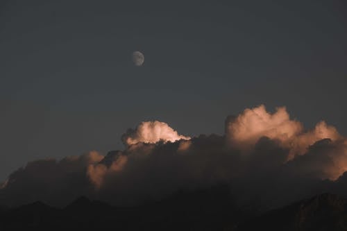 Moon Over the White Clouds on the Mountain Peaks