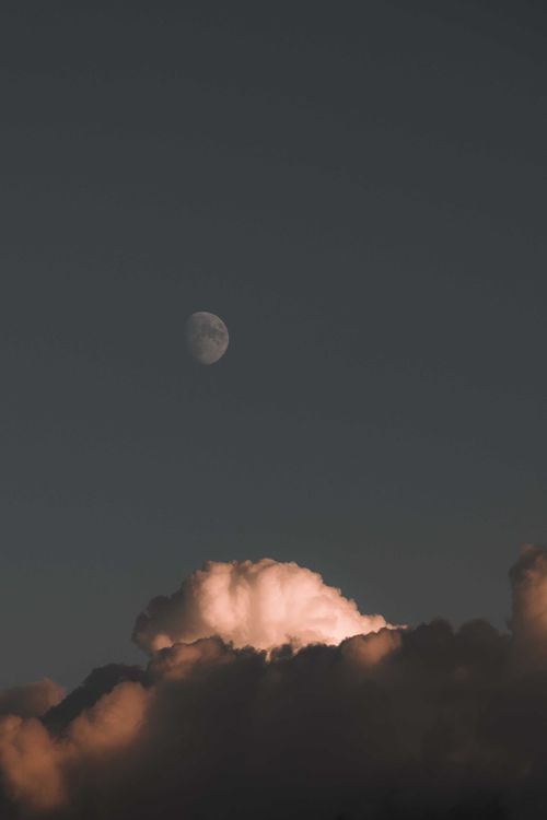 Free Dramatic view of the moon rising above illuminated clouds during evening twilight. Stock Photo