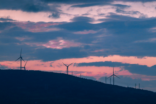 Free Wind turbines silhouette against a dramatic sunset sky, symbolizing renewable energy. Stock Photo