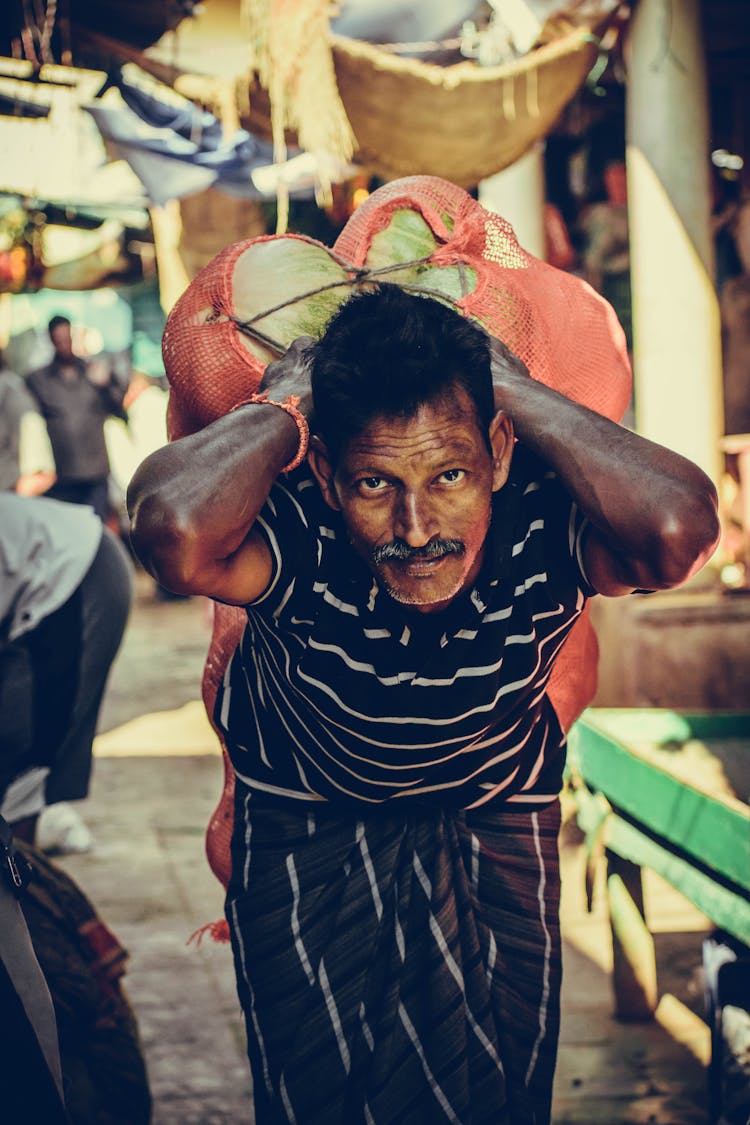 Porter Carrying Heavy Vegetables On Back At Bazaar