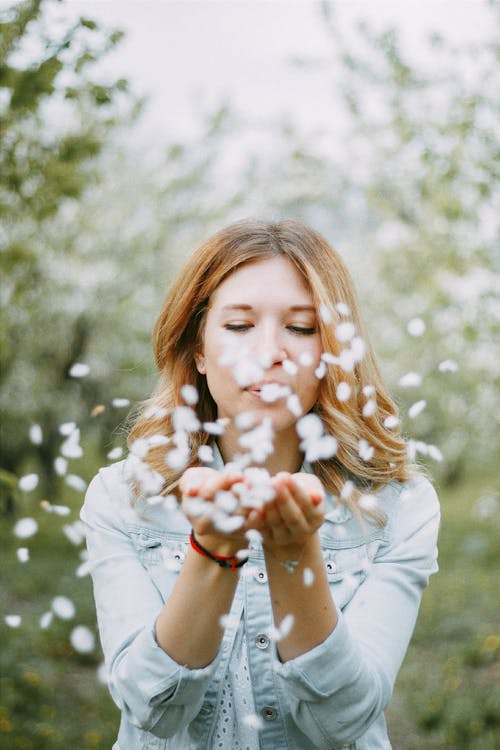 Free Woman Blowing White Petals in Orchard Stock Photo