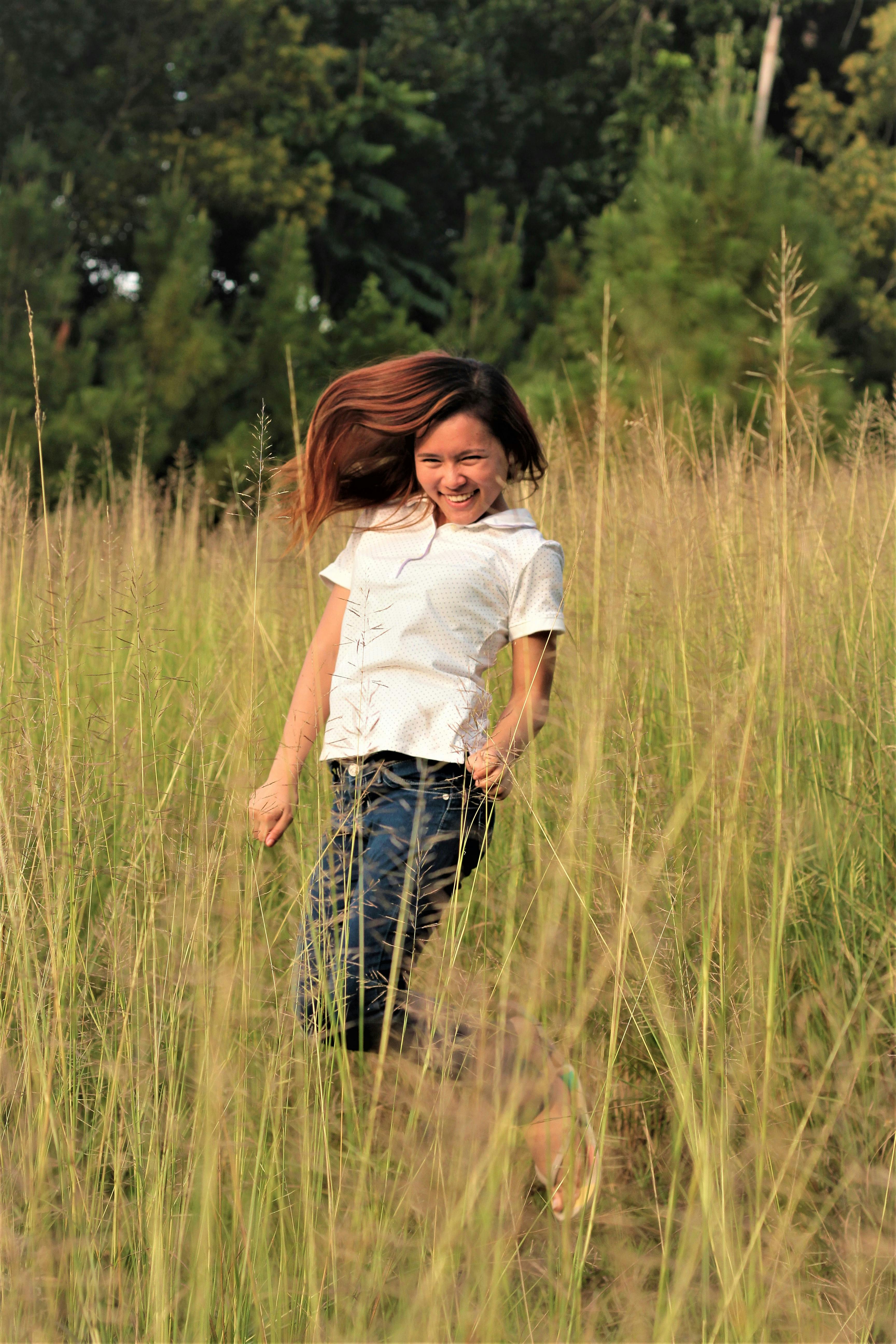 阳光普照的草地上，一个表情愉快的年轻女孩正在嬉戏