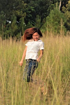阳光普照的草地上，一个表情愉快的年轻女孩正在嬉戏