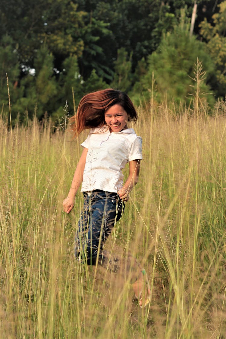 Woman Jumping Between Grass