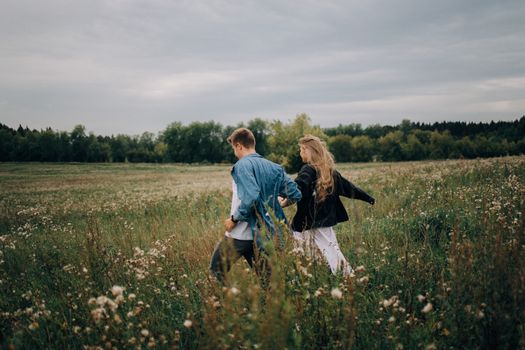 A Back View of Couple Running on Field 