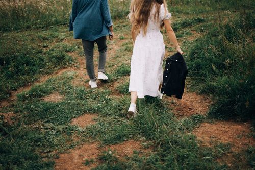 Free A couple strolls through a lush green meadow in summer, capturing a serene outdoor moment. Stock Photo