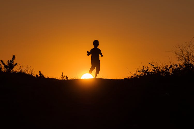 Silhouette Of Child Running During Sunset