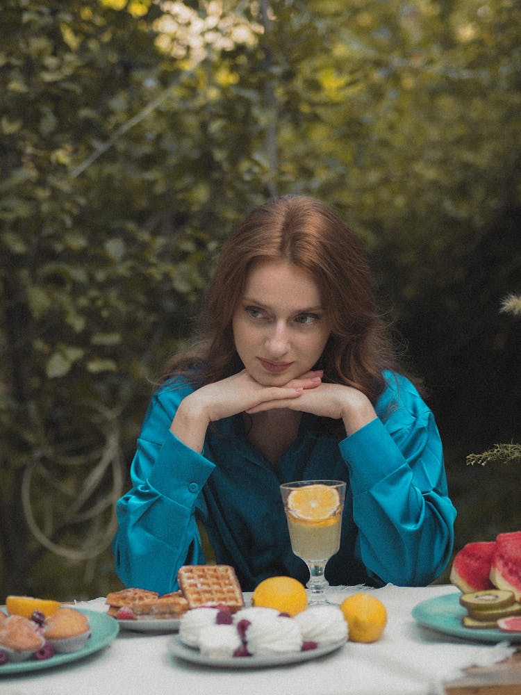 Woman In Turquoise Pyjamas Sitting At Breakfast Table In Garden