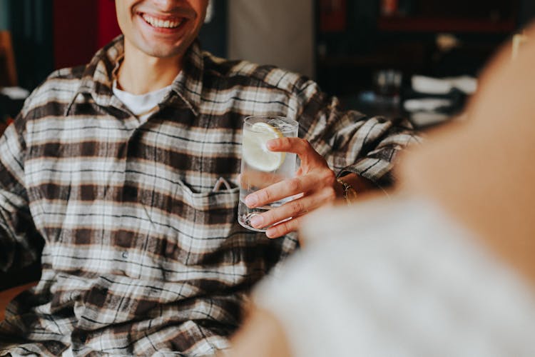 Man Holding Glass Of Water With Lemon Slice 