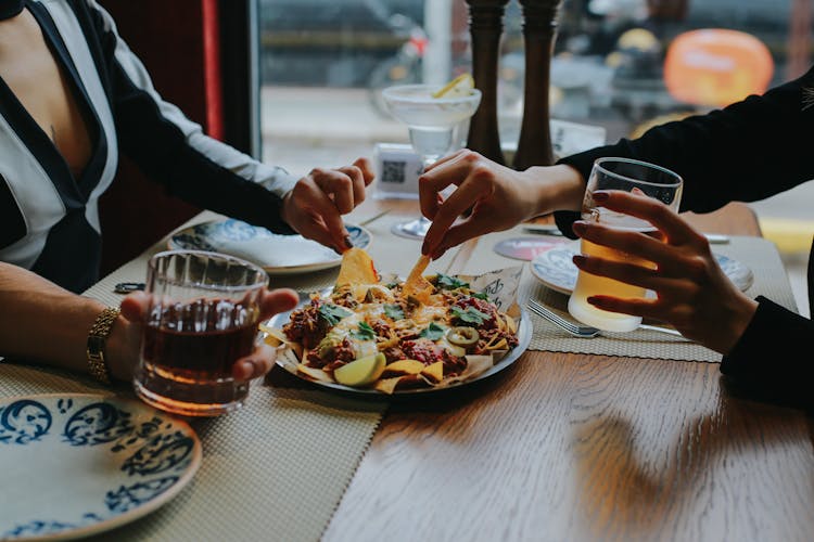 Close-up Of Friends Sharing Food At Restaurant Table