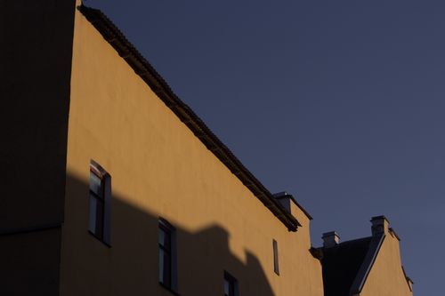 Free A captivating view of a yellow building facade as shadows create contrast at dusk. Stock Photo