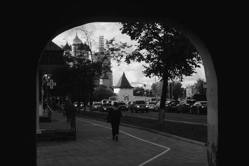 Free Urban black and white photo capturing traffic and architecture through an archway. Stock Photo