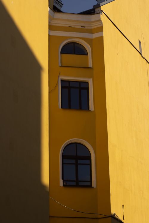 Free Close-up of a yellow building with arched windows, capturing urban architectural details. Stock Photo