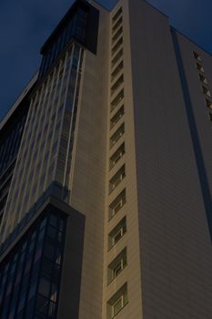 Dramatic low angle shot of a modern skyscraper at dusk, highlighting windows and patterns.