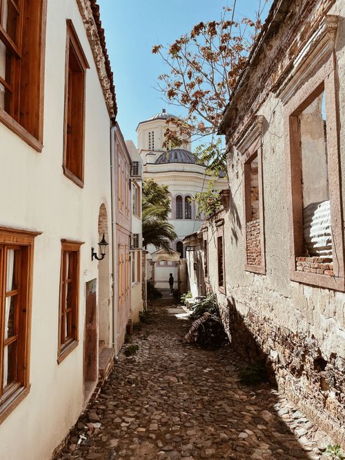 Free Explore a narrow cobblestone alley in Balıkesir, Türkiye, bordered by rustic architecture and a distant dome. Stock Photo