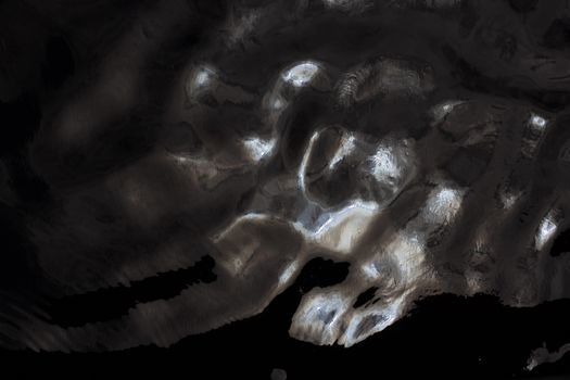 Abstract aerial coastline with shimmering light and shadows on water surface.