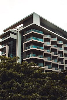 Low angle view of a modern residential building with balconies amidst greenery.