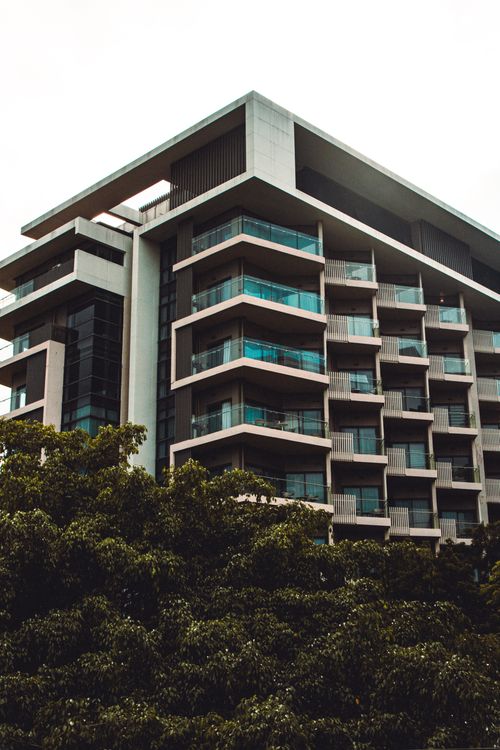 Free Low angle view of a modern residential building with balconies amidst greenery. Stock Photo