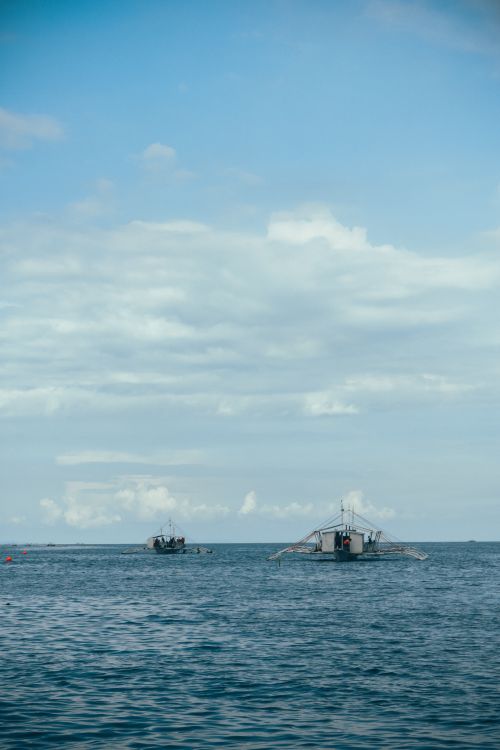 Free Tranquil scene of traditional fishing boats on the ocean under a blue sky. Stock Photo