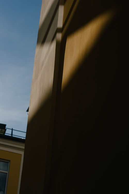 Free Low angle view of sunlight casting dramatic shadows on a concrete wall in an urban setting. Stock Photo