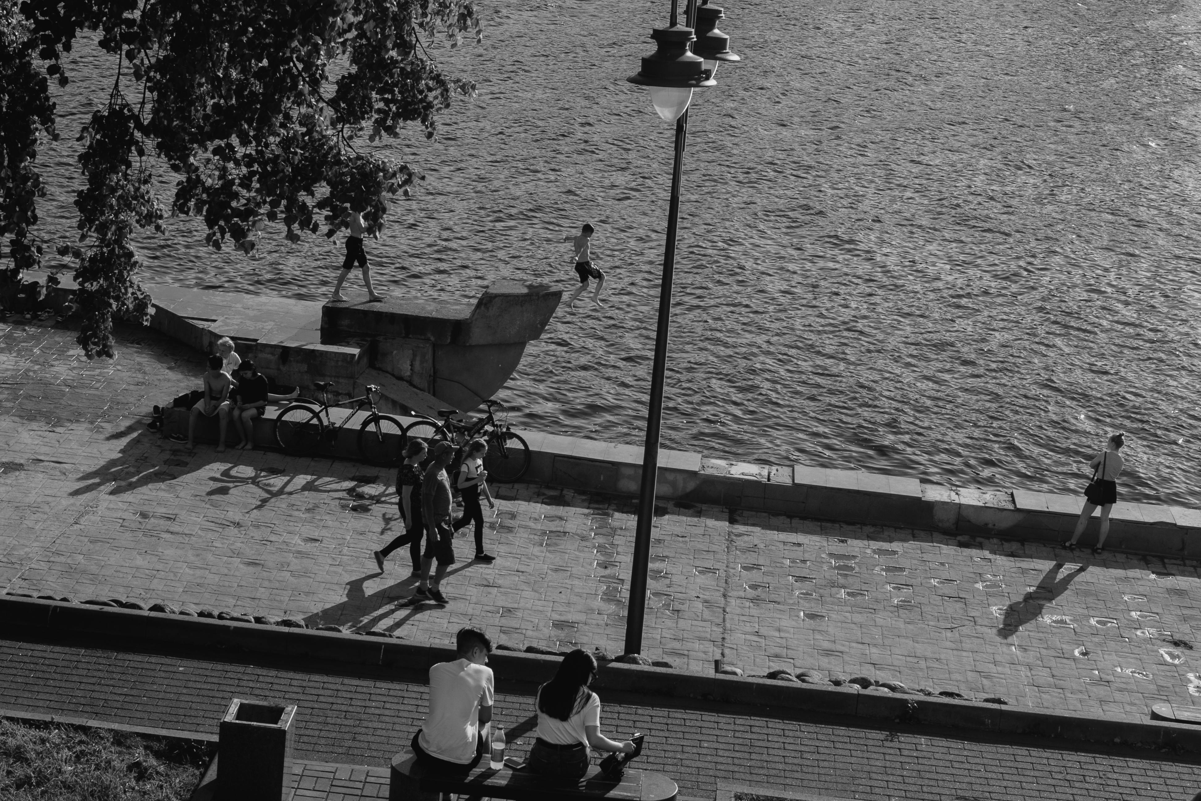 A black and white scene capturing people enjoying a summer day by the seaside promenade.