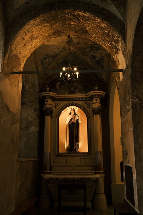 Free A peaceful statue of Saint Mary illuminated in an ancient church interior, capturing religious tranquility. Stock Photo
