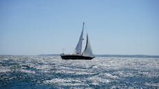 夏日阳光明媚，一艘帆船优雅地航行在康沃尔海岸波光粼粼的海面上