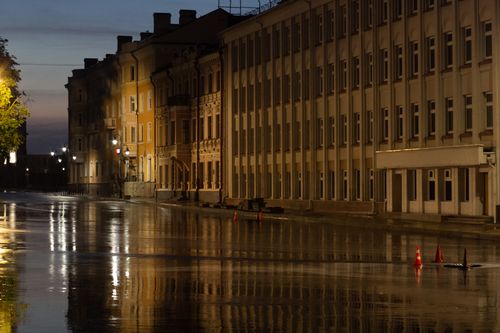 Free A serene urban scene featuring wet roads and well-lit historic building facades at dusk. Stock Photo