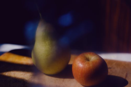 Free Close-up of apple and pear on a wooden cutting board with artistic lighting. Stock Photo