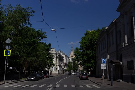 Quiet urban street with parked cars, blue sky, and pedestrian crossing.
