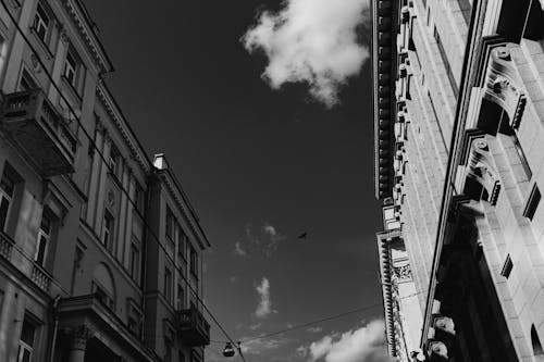 Black and White Photo of Townhouses and Clouds in Sky