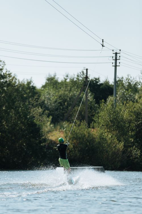 Free Person enjoying wakeboarding on a serene lake, showcasing outdoor adventure. Stock Photo