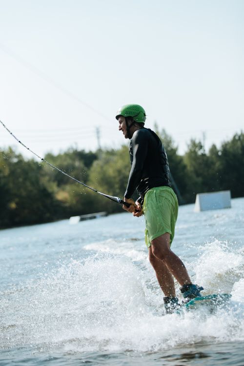 Free Energetic scene of a man wakeboarding on a sunny day with clear skies and splashy water. Stock Photo