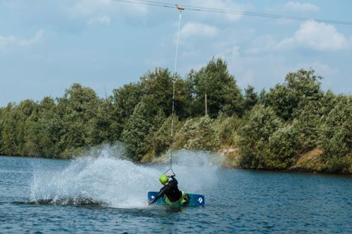 Free Thrilling wakeboarding stunt captured on a sunny day with energetic water splash effects. Stock Photo