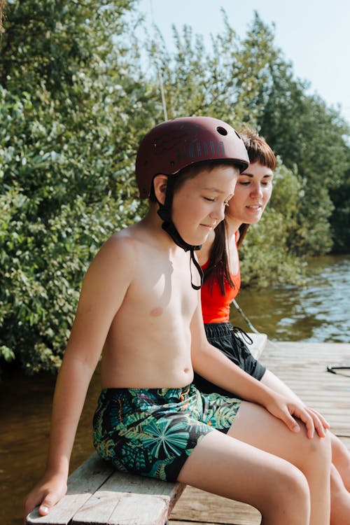 Boy in Helmet Sitting on Jetty