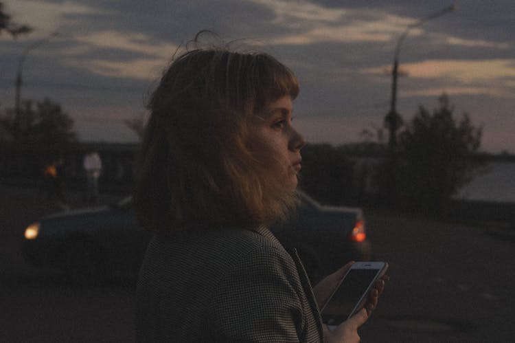 Side View Of A Woman Holding An Iphone